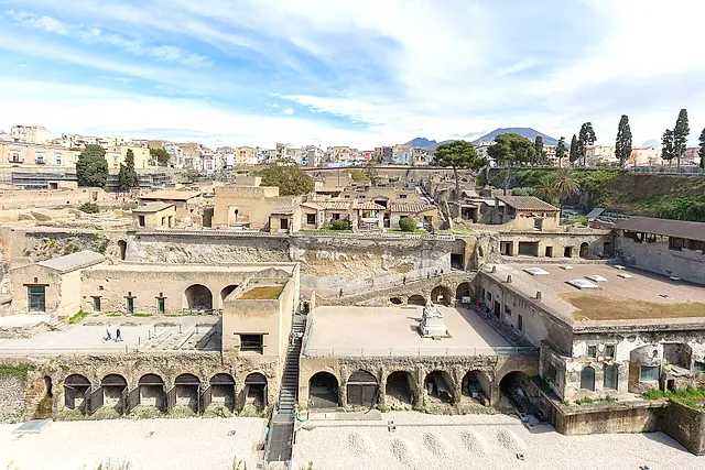Excavations of Herculaneum with the boathouse arches, the modern town and Mount Vesuvius behind